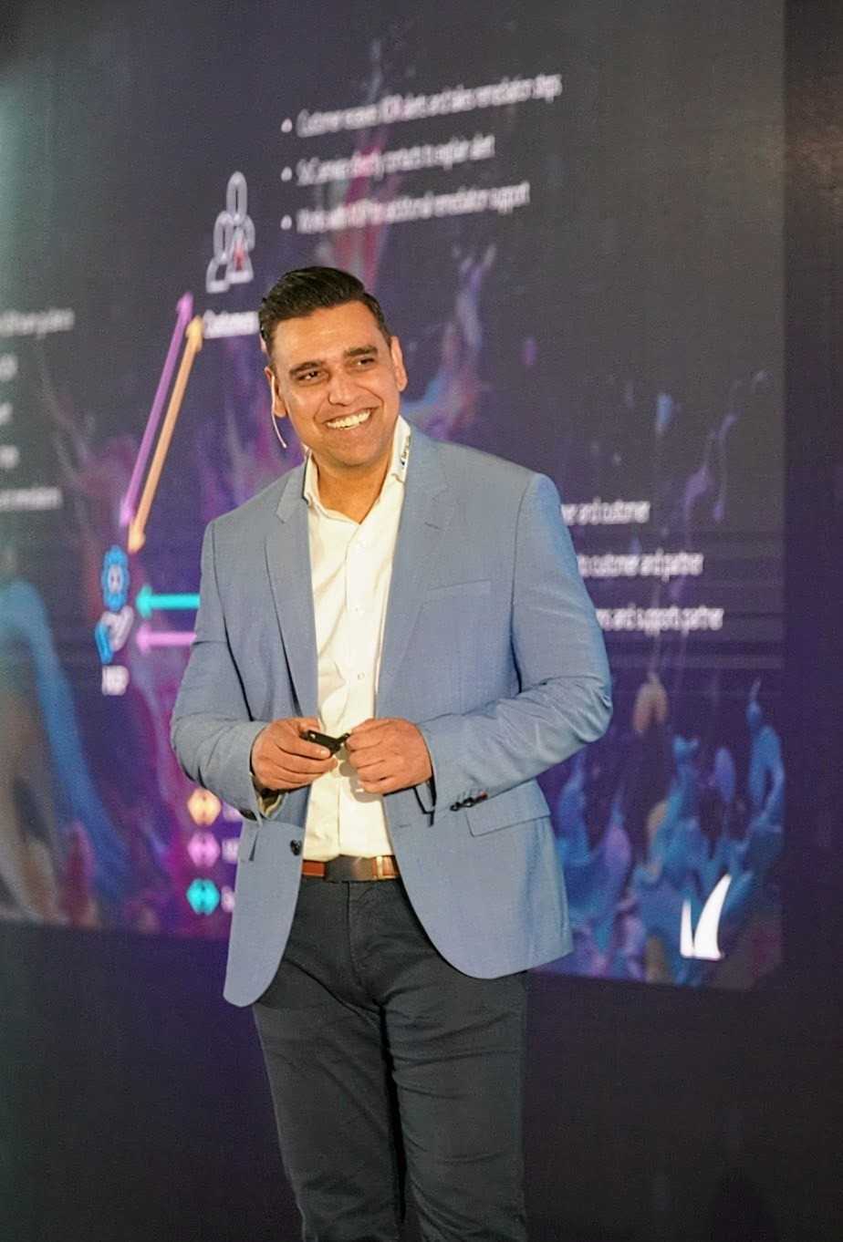 Adam Khan delivering a keynote in a blue suit on stage at Barracuda Discover24 AMER